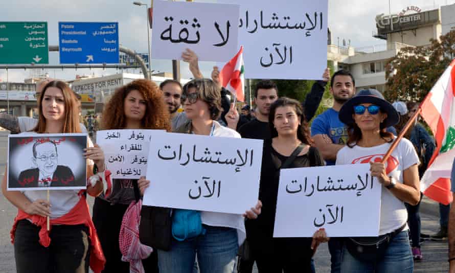 Protesters carry a Lebanese flag and placards as they block the road to the presidential palace in east Beirut on 1 November.
