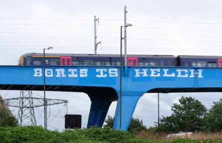 The words Boris is Helch written in white on a blue railway bridge. A train is travelling overhead.