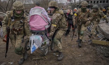 Ukrainian soldiers help families fleeing the town of Irpin on Saturday