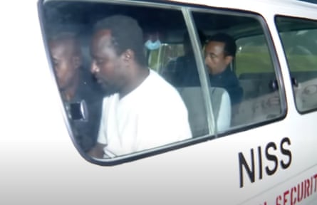 An African man with two others in a van marked with the name of the Ethiopian intelligence agency NISS