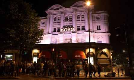 The facade of an impressive white-painted theatre-style building, illuminated at night