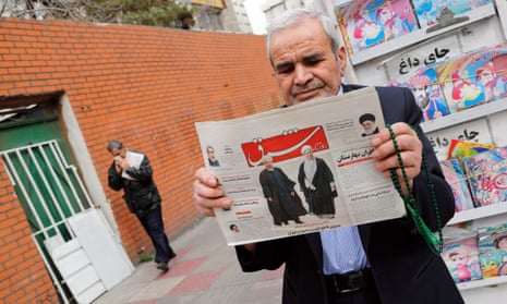 A man holds a copy of the daily Shargh newspaper with pictures of Iranian President Hassan Rouhani and former president Akbar Hashemi Rafsanjani.