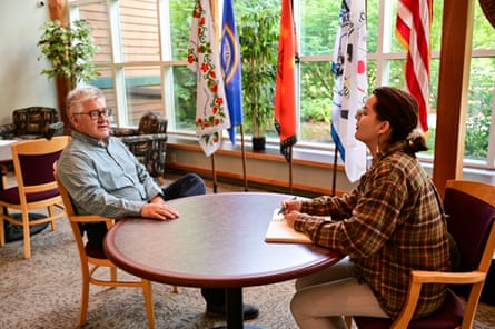 a man and a woman speak while seated at a table