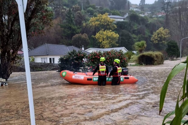 Emergency personnel with a rescue boat stand in flood waters