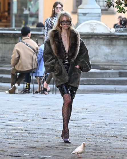 Woman on street in jacket with fur-style oversized collar, short skirt and big sunglasses