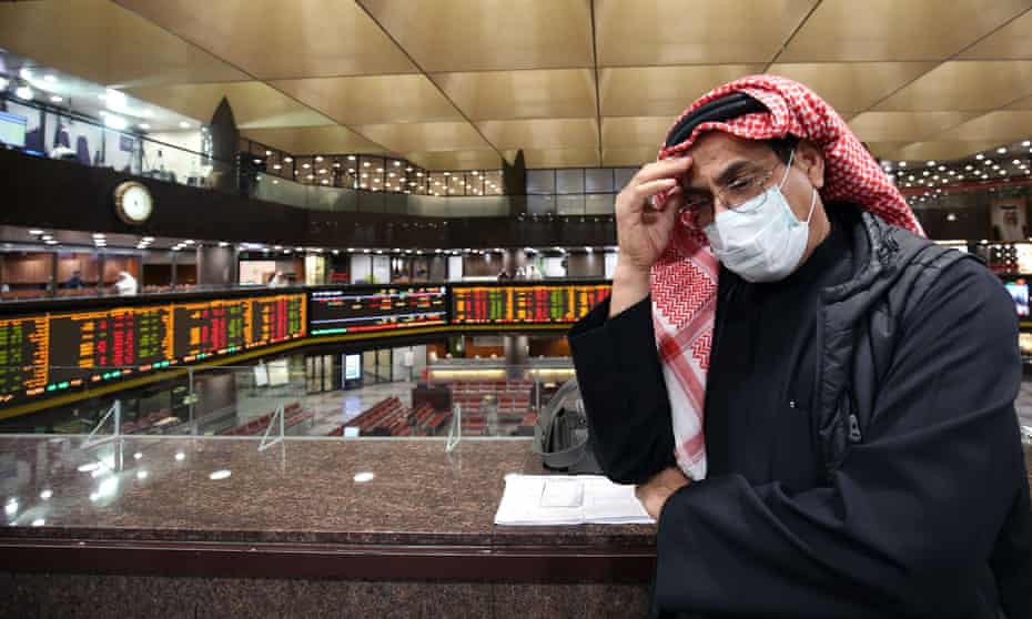 A trader wearing a protective mask follows the market at the Boursa Kuwait stock exchange in Kuwait City.