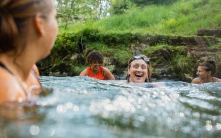 Group of women wild swimming in the Lake District, North West of England. They are in a river, enjoying time outdoors.