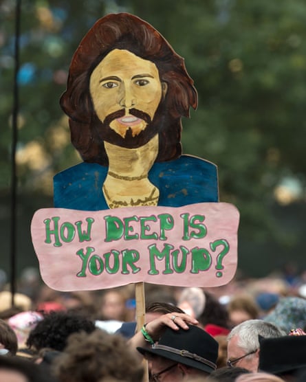 A fan holds up a “How deep is you mud?” banner during Barry Gibb’s set at Glastonbury
