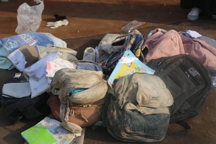 A collection of school bags covered in concrete dust.