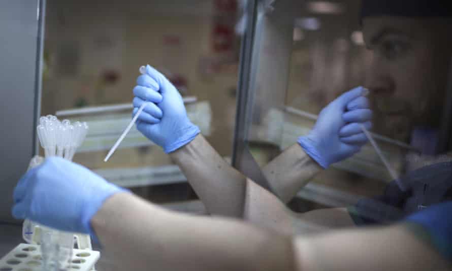 Embryologist Brad Wilson is seen in a glass reflection while placing a sperm sample onto a counting chamber as he prepares the sample for insemination.