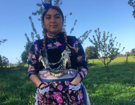 A young woman in a floral dress with big necklaces and braided hair