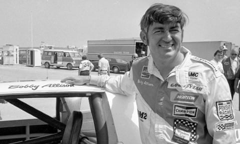 Bobby Allison stands beside his car and talks with the press after winning the pole position during qualifying for a 1975 race at Pocono Raceway in Long Pond, Pennsylvania.