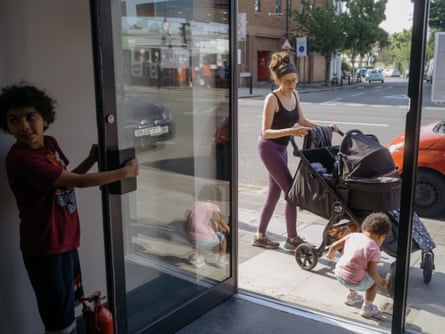 A woman pushes a buggy with a young child playing next to the wheels