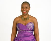 Marcia Hutchinson smiles, wearing hoop earrings, a beaded necklace, and a purple strapless dress