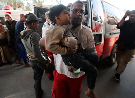 A member of Palestine Red Crescent Society carries a Palestinian child as the wounded are rushed into Nasser hospital following Israeli strikes in Khan Younis.