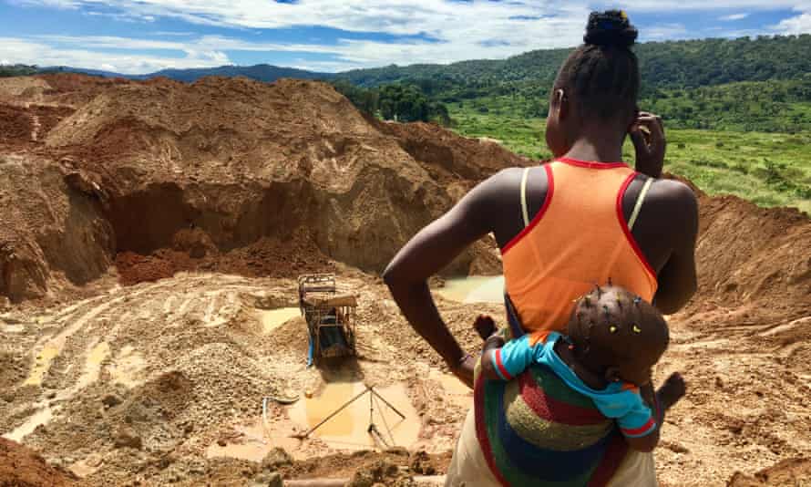 A woman with a baby stares into an abandoned gold mine