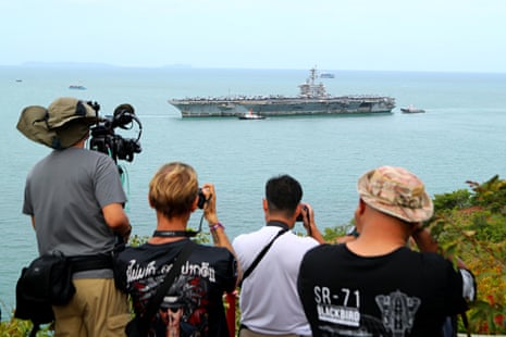 Photographers take pictures of the ship seen in the sea in the distance.