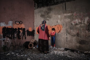 a woman in a traditional Turkish scarf is seen from behind talking to a grumpy looking book in a spiderman costume