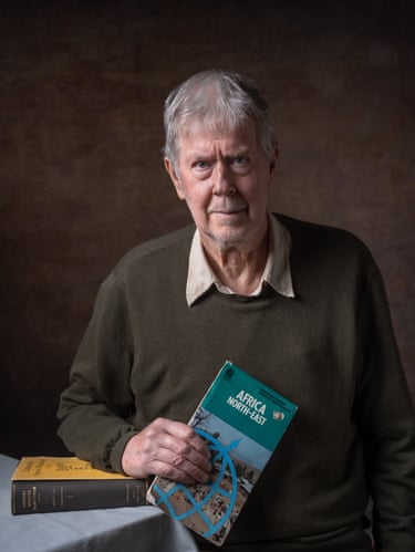 A man holds a map and rests his arm on a book