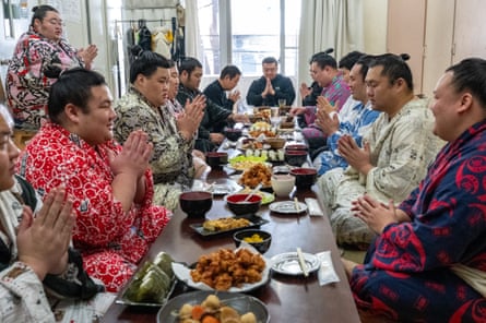 They sit around a low wooden table dressed in traditional clothing