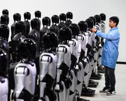 An engineer at the AgiBot factory in Shanghai, China, where the 5,000th mass‑produced humanoid robot had rolled off the production line. Photograph: China News Service/Getty Images