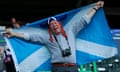 Man in viking hat hoists a Scotland flag in the stands of Celtic Park.