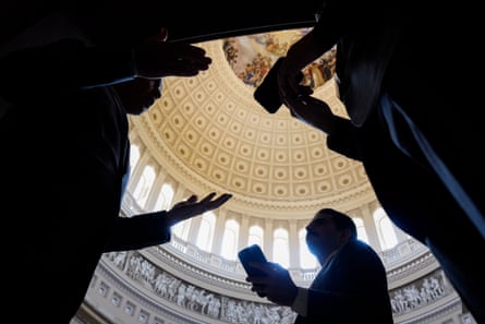 Seen in silhouette from below, people gesture as they speak beneath a vaulted dome.