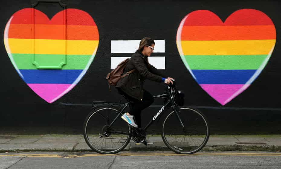 A woman cycles past a marriage equality mural