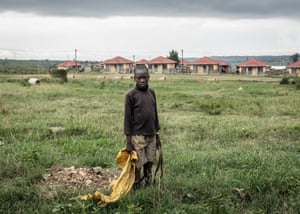 Young man stands in field with new houses behind him