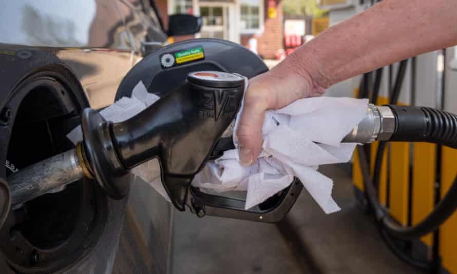 A motorist fills their petrol tank using a paper towel to help prevent the spread of Coronavirus