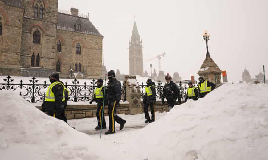 Police officers walk pass the Parliament buildings in Ottawa on Sunday.