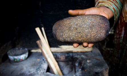 A parent in Cameroon heats a stone to iron the breasts of her daughters.