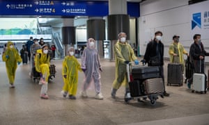 Travellers in full protective gear arriving at Hong Kong international airport.