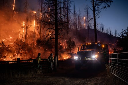 A fire engine drives past a group of firefighters along a control line