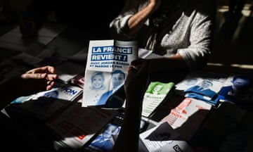A person holds a flyer that reads ‘La France revient !’ (France is back!) featuring JOrdan Bardella and Marine Le Pen of the National Rally party.