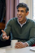 Rishi Sunak sitting at a table holding a mug and wearing a green quarter-zip sweater