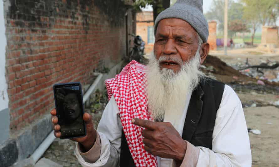Nasim Ahmed, 74, points to a photo of his dead son, Kamran, on a mobile phone
