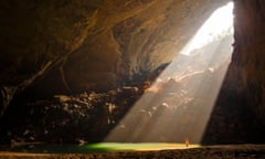 A caver stands in a sunbeam coming through an entrance to Hang En Cave in Phong Nha Ke Bang National Park, Vietnam