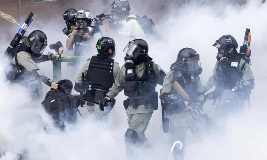 Police in riot gear move through a cloud of smoke as they detain a protester at the Hong Kong Polytechnic University 