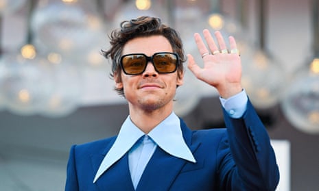 Harry Styles wearing sunglasses and waving 