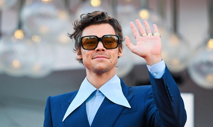Harry Styles wearing sunglasses and waving