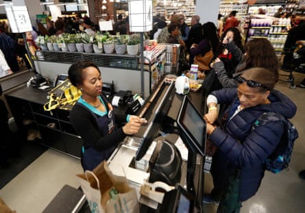 A cashier, left, checks out items as a customer shops during the grand opening of the Whole Foods supermarket in Newark, N.J.