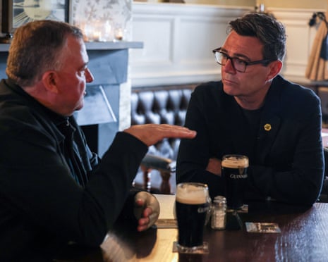 Andy Burnham sits with a pub landlord, each nursing a pint of Guinness