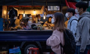 Pedestrians wearing face masks walk past a food stall on a street in Seoul.