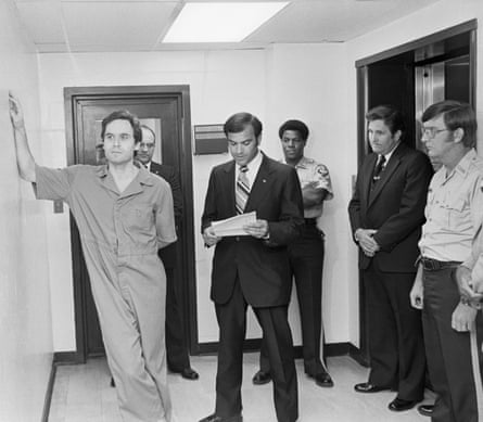 Ted Bundy (l) leans on the Leon County jail wall as an indictment charging him with the murders of two women is read to him.