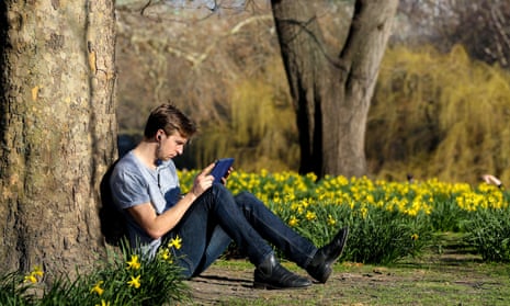 a man sits on short-sleeve shirt among the daffodils in a park