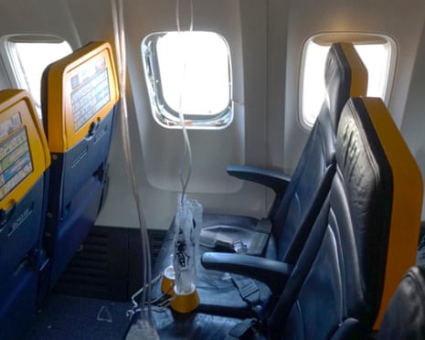 The shattered window on the Ryanair plane with oxygen masks on the seats