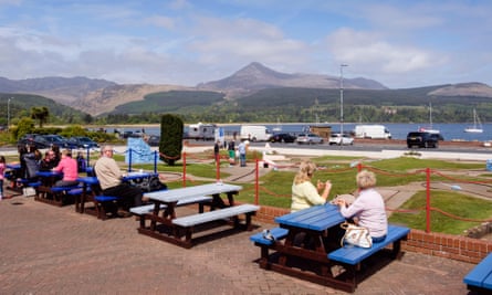 Tourists on the isle of Arran with a view to Goat Fell mountain across Brodick Bay.