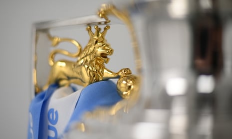 The Premier League trophy with Manchester City coloured blue and white ribbons.