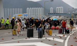 Passengers walk to a terminal as protesters block the roads leading to Hong Kong’s international airport